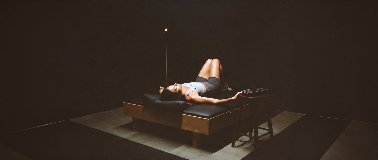 Woman resting on a PEMF therapy bed in a dark studio