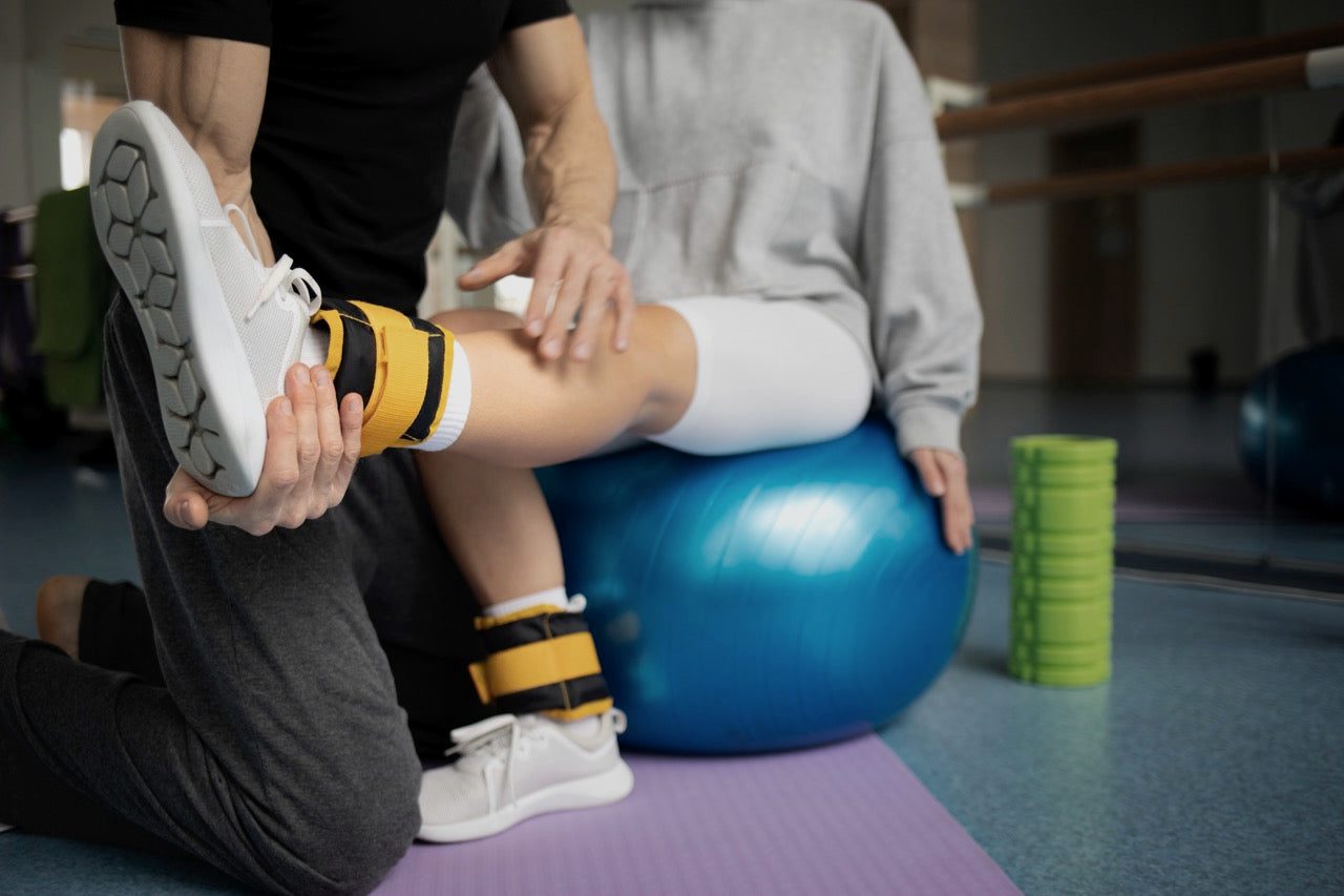 Therapist guiding a seated leg exercise on a stability ball