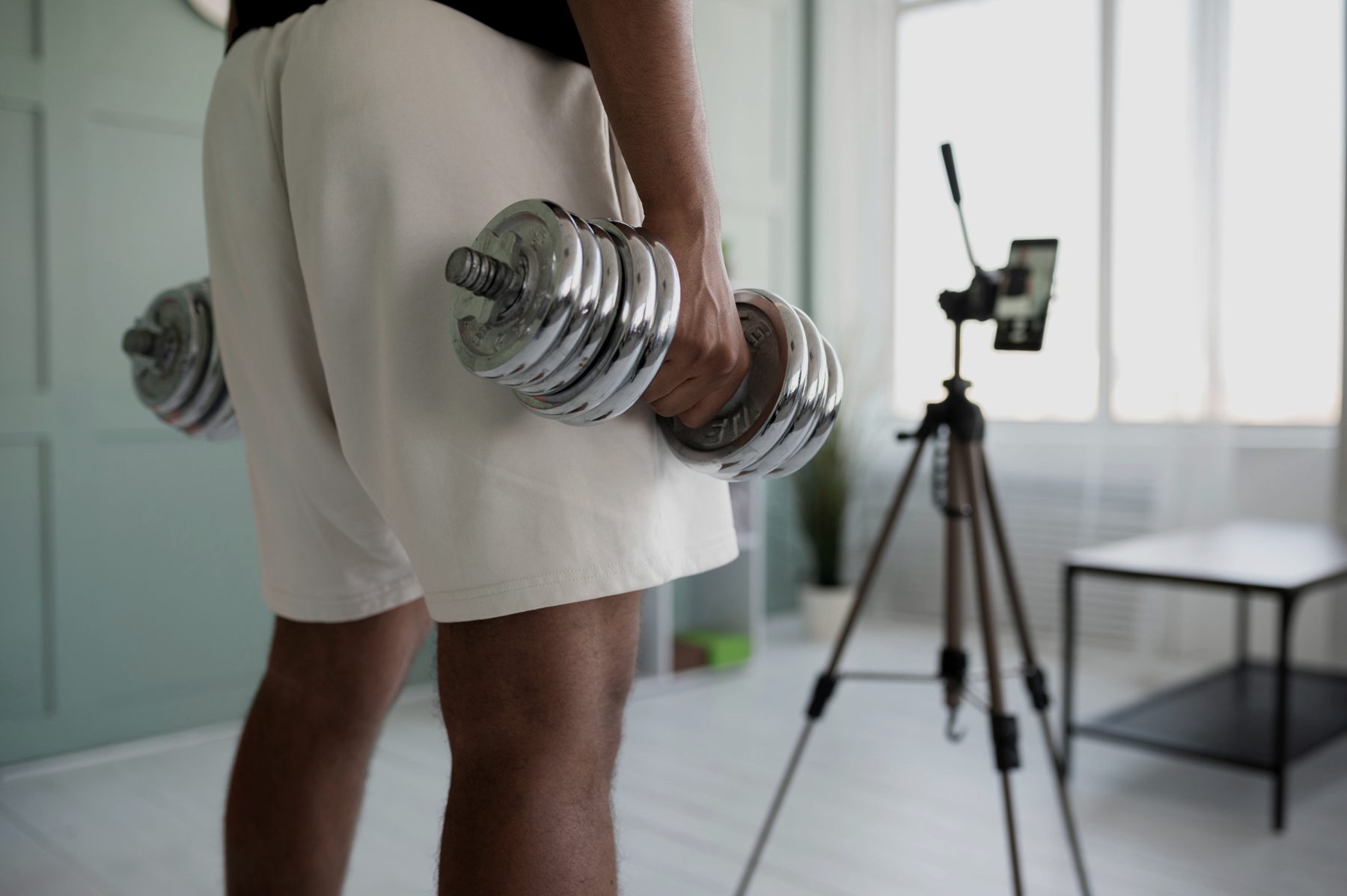 Hands holding a pair of dumbbells at the side