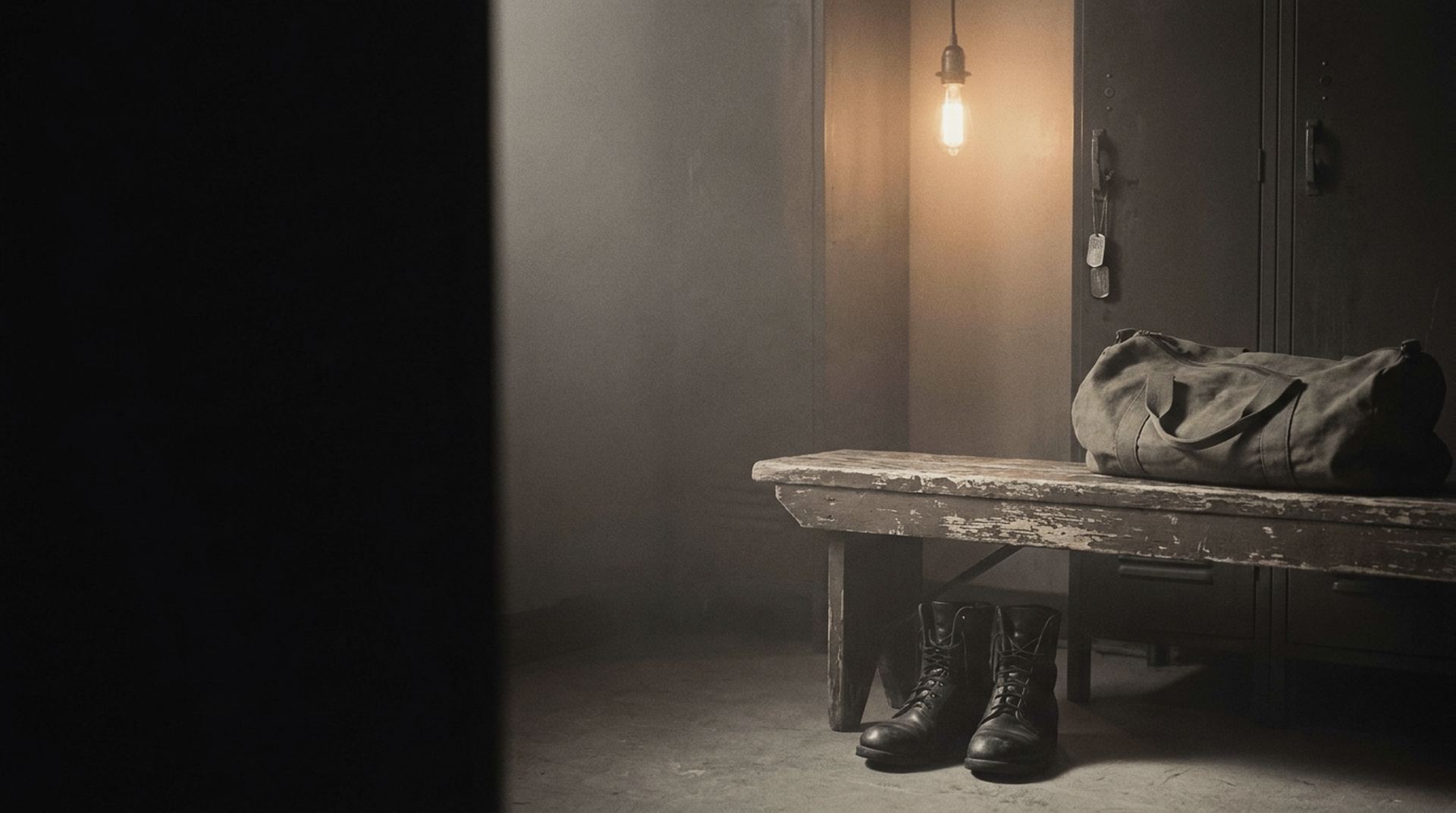 A dim locker room: a worn bench, laced boots, a canvas duffel, and dog tags on a locker hook under one lamp