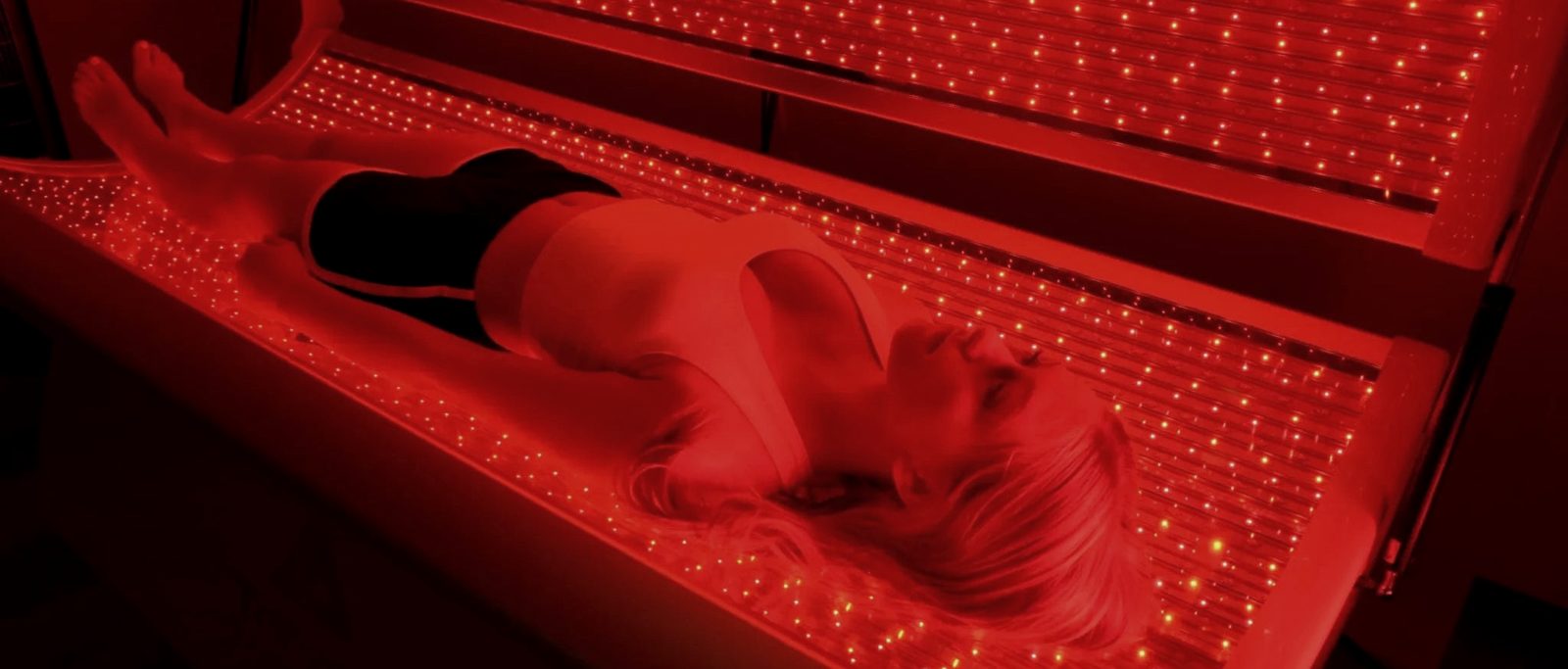 Person lying in a full-body red light bed